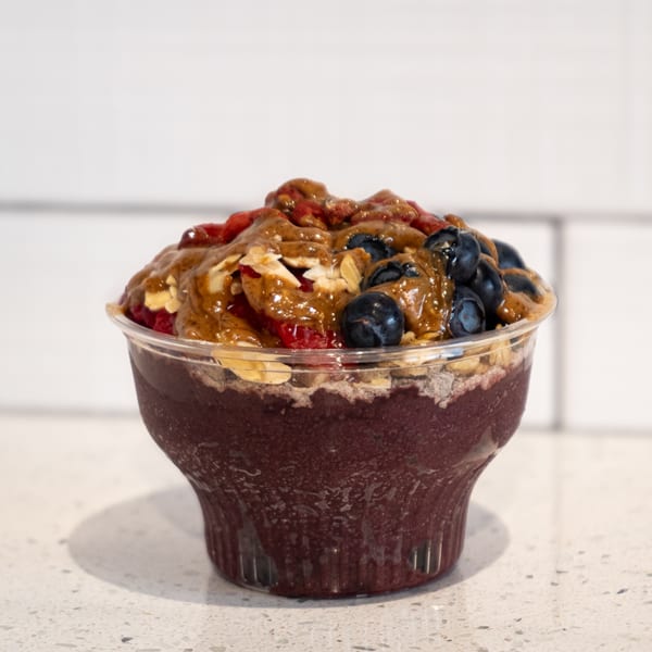 A bean THERE acai bowl with blueberries, goji berries, sliced almonds, and peanut butter drizzle.