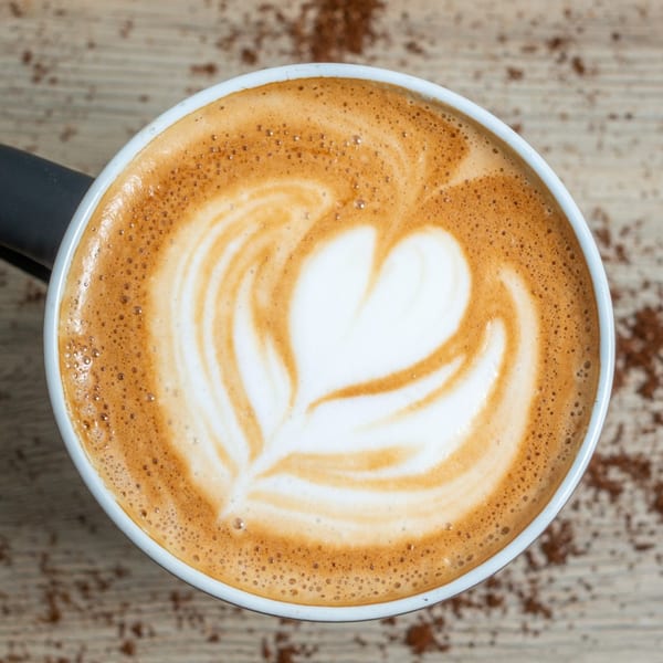 Overhead view of a latte with a heart-shaped latte art design, on a wooden surface.