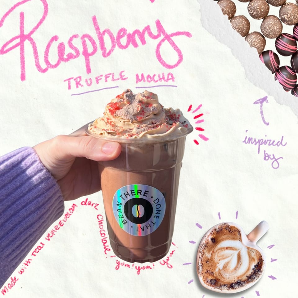 Hand holding a Bean There Done That Raspberry Truffle Mocha with whipped cream and sprinkles.